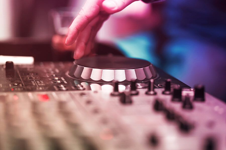 Club DJ playing mixing music on vinyl turntable at party